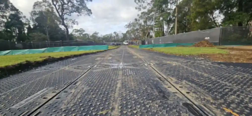 Ground protection mats laid as a temporary site access road over turf